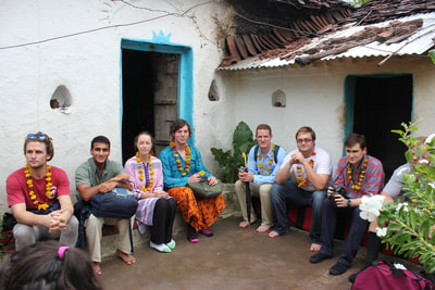 Students sitting in a local home talking with the family, 2015