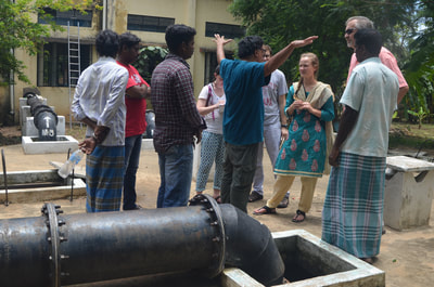 Water team talking with locals behind a pipe