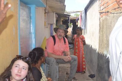 Students and program director meet with family in the street outside their home, 2015