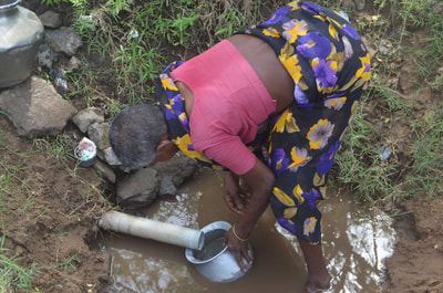 Woman collecting water from a pipe